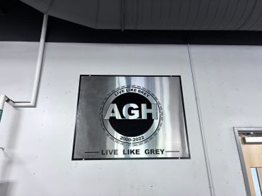 Metal plaque with AGH and 'Live Like Grey' inscription.