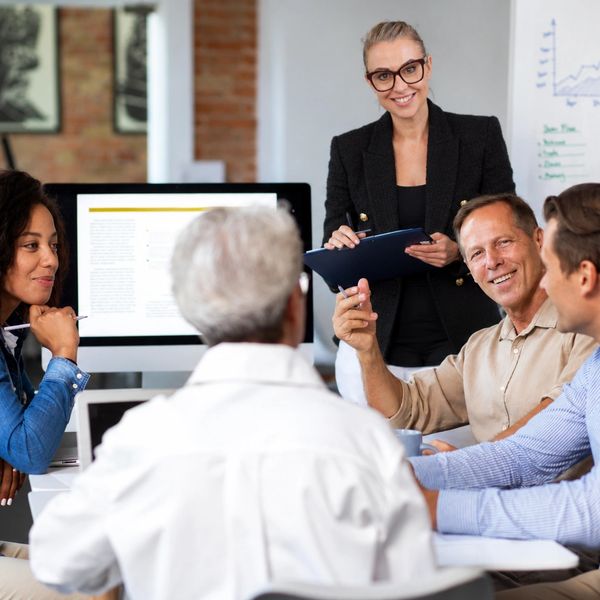 Team meeting with a woman presenting and her colleagues engaged.