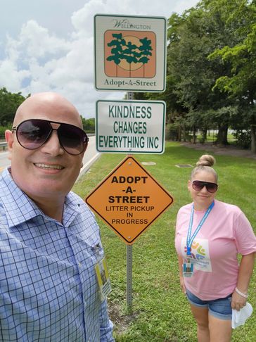 Two people posing near an Adopt-A-Street sign in Wellington.