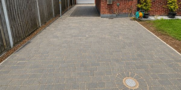 Newly paved driveway with grey bricks and a drain.