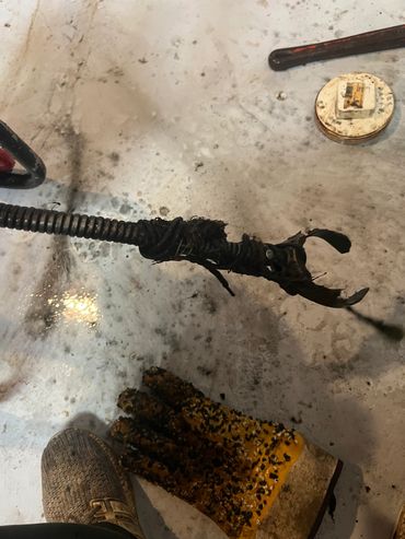 Burnt wire and a work glove on a dirty floor.