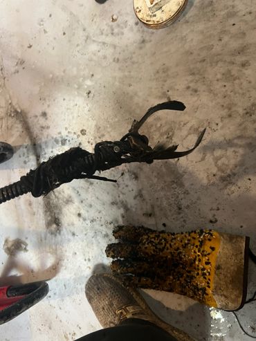 Burnt wire and debris on a dirty floor with gloves and a shoe.