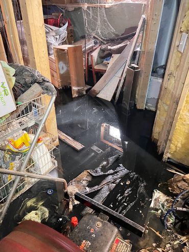 Flooded basement filled with debris and furniture.