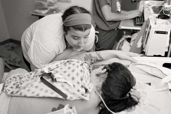A woman comforting a patient lying in a hospital bed.