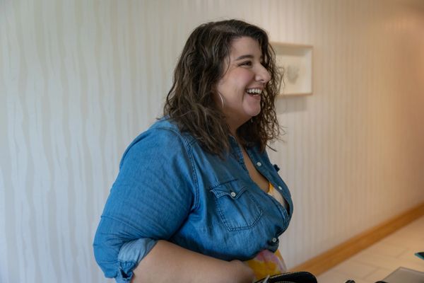 Smiling woman in a denim shirt indoors.
