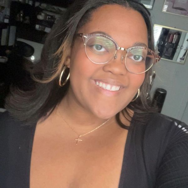 Smiling woman wearing glasses and hoop earrings.