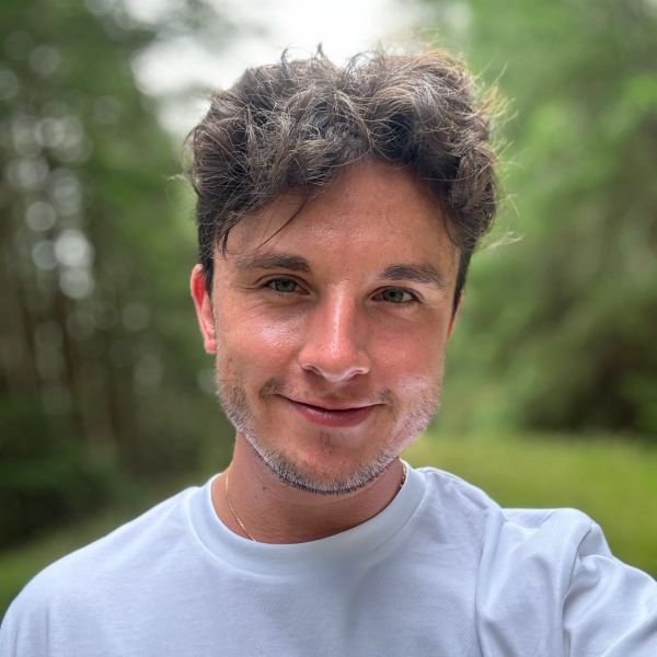 Young man with a slight smile in a natural outdoor setting.