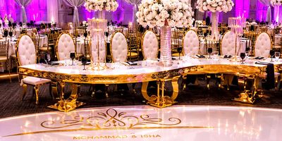Elegant wedding reception setup with gold accents and floral centerpieces.