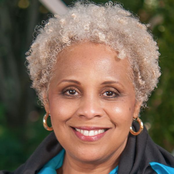 Smiling woman with curly blonde hair and hoop earrings.