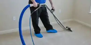 Person professionally cleaning a carpet with a machine in an empty room.