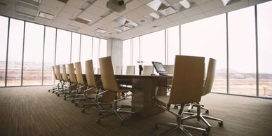 Modern conference room with large windows and leather chairs around a wooden table.