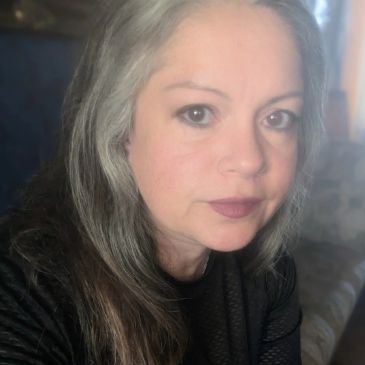 Woman with gray and dark hair looking at the camera.