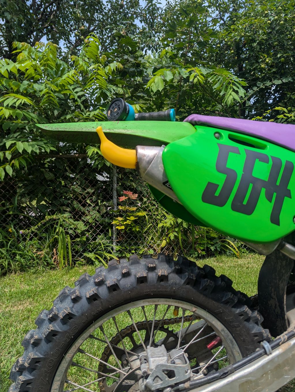 Close-up of a green dirt bike with the number 567 and a yellow muffler tip.