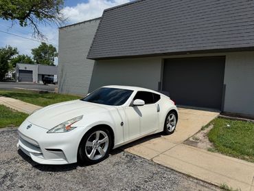 White sports car parked near a gray building on a sunny day.