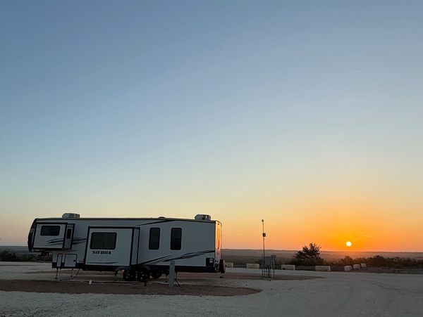 A trailer parked at sunset in a vast open area.