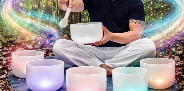 Person playing crystal singing bowls surrounded by mystical light effects in a forest.