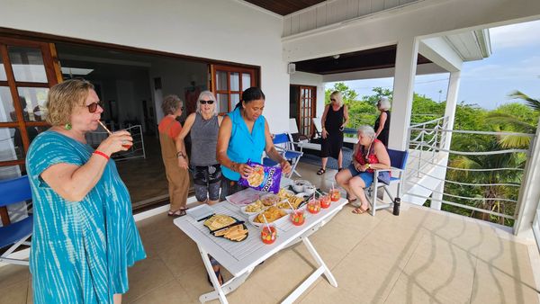 People standing around table having drinks and snacks on veranda
