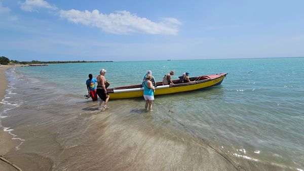 small motor boat in the surf with people sitting inside and others waiting to get in