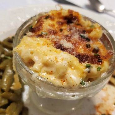 Close-up of creamy baked macaroni and cheese topped with herbs and cheese.