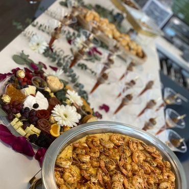A buffet table with shrimp dish and charcuterie platter.