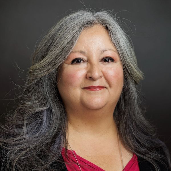 Portrait of a middle-aged woman with long gray hair and a warm smile.
