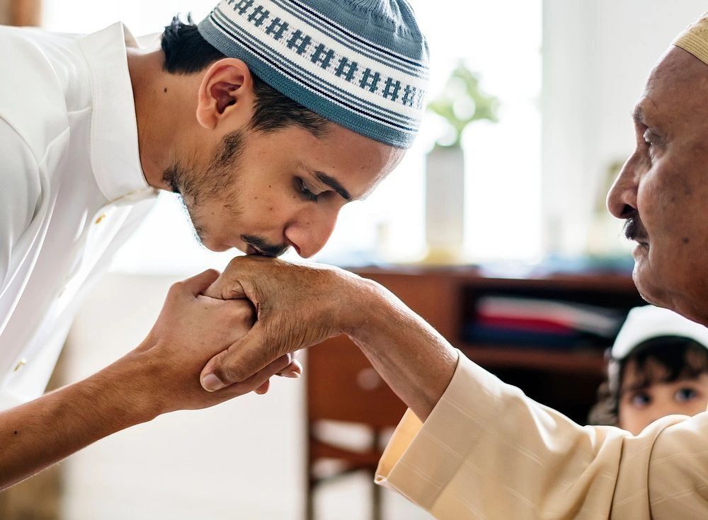 Young man respectfully kisses elder's hand in a traditional gesture.