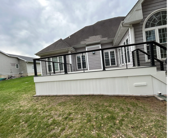 Modern deck with black metal railing attached to a suburban house.