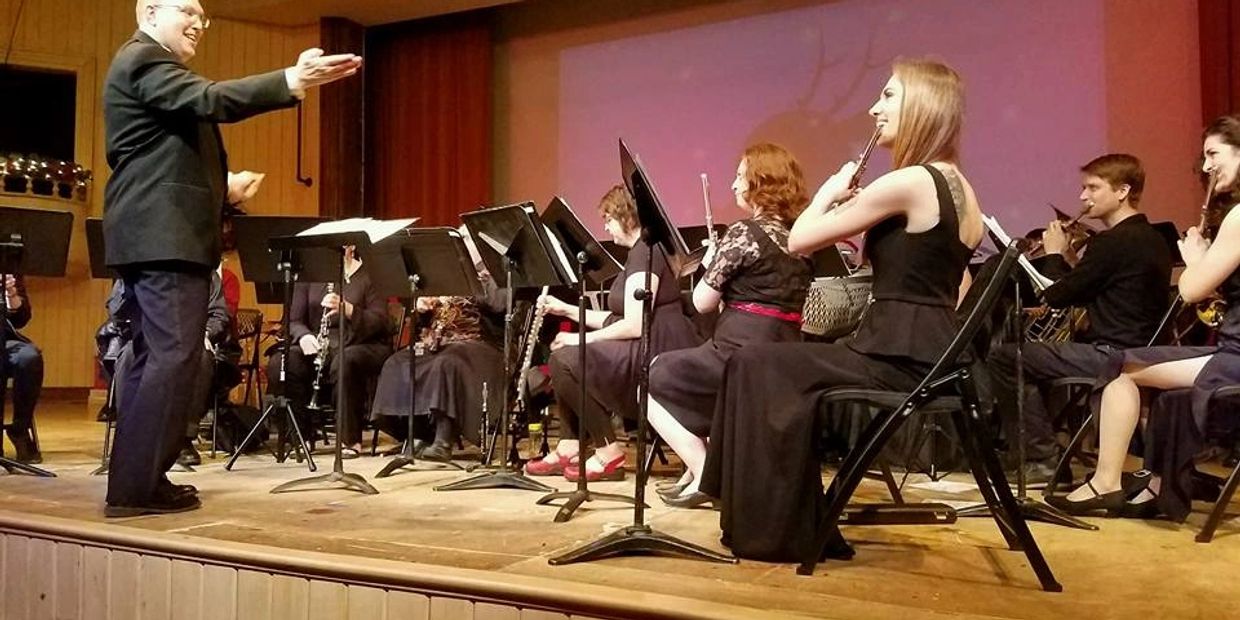 Conductor leading a seated orchestra during a performance.
