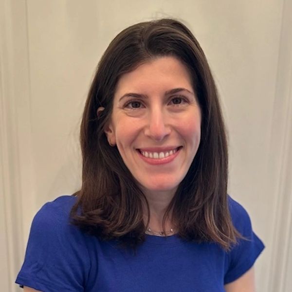 Smiling woman with shoulder-length brown hair wearing a blue shirt.