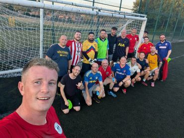 Group photo of soccer players by the goal on a field.