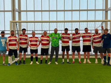 Soccer team lined up in front of goal indoors.