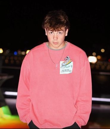 Young man in a pink sweatshirt with an astronaut design at night.