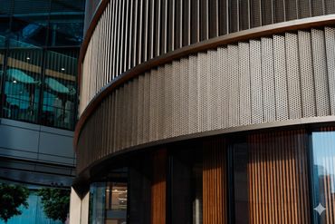 Curved modern building facade with metallic and wooden textures.