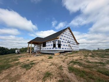 House under construction on a dirt hill.