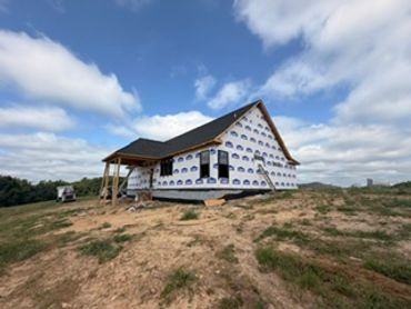 A house under construction on a grassy hill.