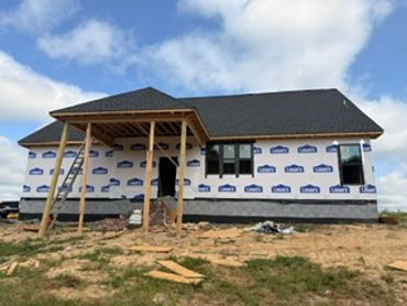Single-story house under construction with a temporary porch roof.