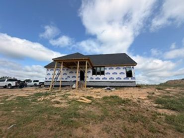 A small house under construction on a grassy hill.