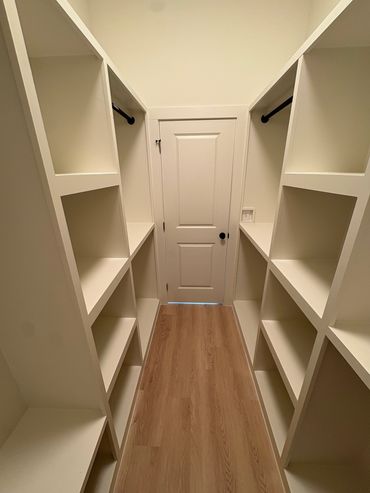 Empty walk-in closet with shelves and hanging rods.