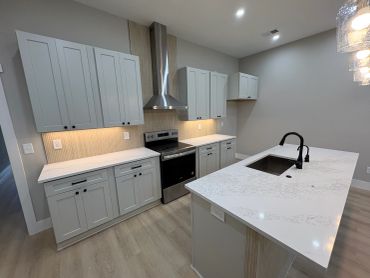 Modern kitchen with white cabinets and marble countertops.