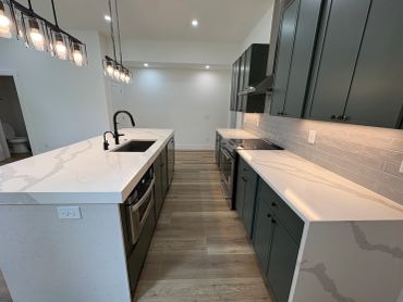 Modern kitchen with marble countertops and dark cabinetry.