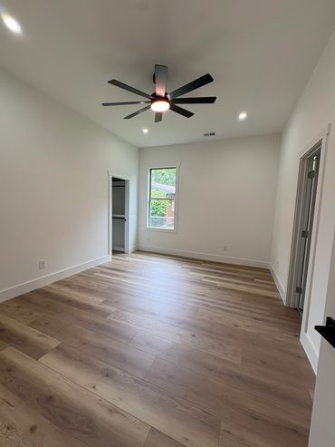 Empty room with wood flooring and ceiling fan.