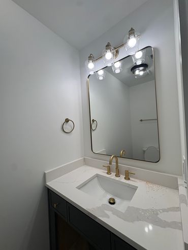 Modern bathroom vanity with gold fixtures and mirror.