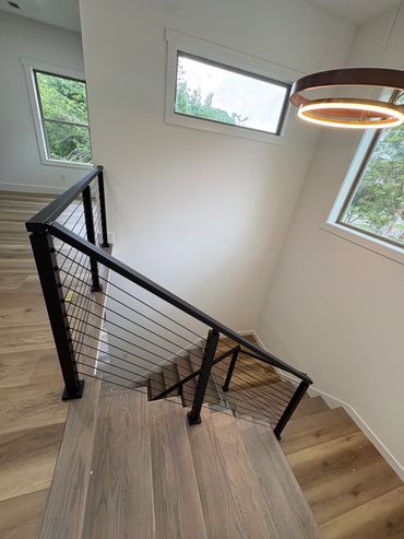 Modern staircase with black railing and large windows.