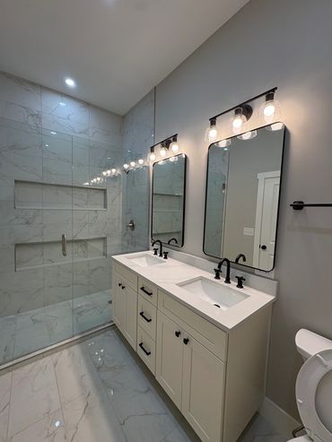 Modern bathroom with double sinks and glass shower.