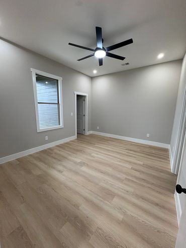 Empty room with ceiling fan and wooden floor.
