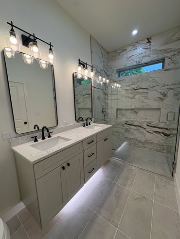 Modern bathroom with double sinks and glass shower.