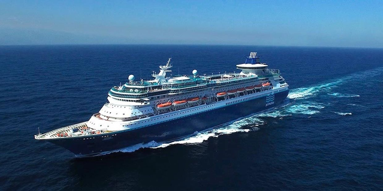 Large cruise ship sailing on calm ocean waters under clear blue sky.