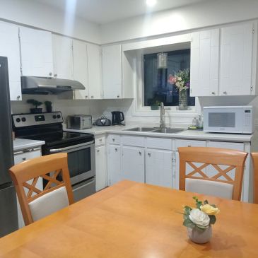 Cozy kitchen with wooden chairs and white cabinets.