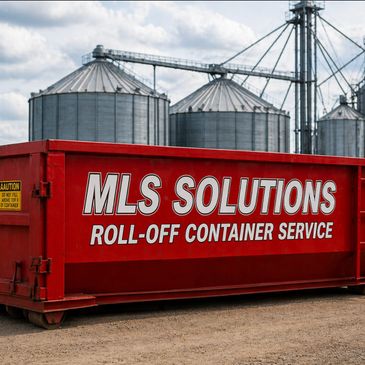 Red roll-off container with MLS Solutions logo by grain silos.