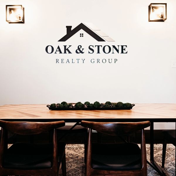 Oak & Stone Realty Group conference room in Cosmopolis, WA, with logo sign between two lights